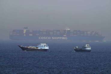 Two traditional dhows sail by a large container ship in the Strait of Hormuz Friday, May 19, 2023. The Mideast-based chiefs of the U.S., British and French navies transited the Strait of Hormuz on Friday aboard an American warship, a sign of their unified approach to keep the crucial waterway open after Iran seized two oil tankers. (AP Photo/Jon Gambrell)