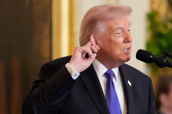 President Donald Trump touches his ear as he talks about the noise from the new ballroom construction before a Medal of Honor ceremony in the East Room of the White House, Monday, March 2, 2026, in Washington.(AP Photo/Mark Schiefelbein)
