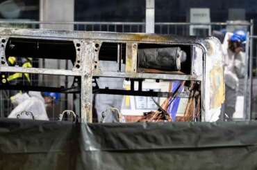 Fire investigators examine the charred shell of a postal bus that caught fire in Kerzers, Switzerland, Tuesday, March 10, 2026, after several passengers were killed and others injured when a postal bus caught fire late Tuesday afternoon in the center of Kerzers, according to the Fribourg cantonal police. (Alessandro della Valle/Keystone via AP)