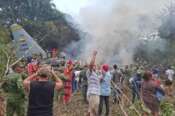 People stand around a military cargo plane that crashed after taking off from Puerto Leguizamo, Colombia, a remote municipality in the Amazonian province of Putumayo, Monday, March 23, 2026. (MiPutumayo via AP)