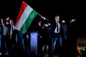 Peter Magyar, leader of the opposition Tisza party, waves the Hungarian flag following the announcement of the partial results of the parliamentary election, in Budapest, Hungary, Sunday, April 12, 2026. (AP Photo/Denes Erdos)
