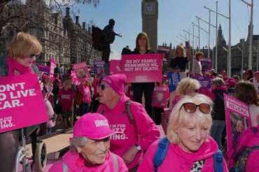 Christie Arntsen, a terminally ill woman, center, stages a protest outside the Houses of Parliament days ahead of the assisted dying bill, in London, Wednesday, April 22, 2026. (AP Photo/Kin Cheung)