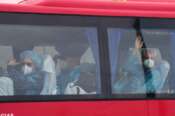 Passengers wave inside a bus after being disembarked from the hantavirus-stricken cruise ship MV Hondius at the port of Granadilla in Tenerife, Canary Islands, Spain, Sunday, May 10, 2026. (AP Photo/Manu Fernandez)