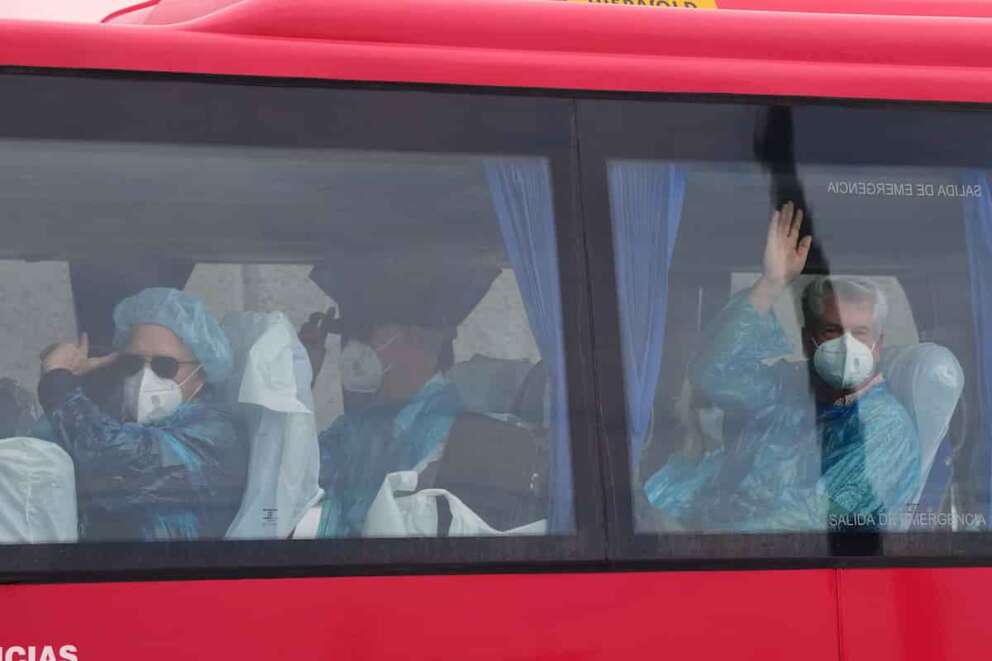 Passengers wave inside a bus after being disembarked from the hantavirus-stricken cruise ship MV Hondius at the port of Granadilla in Tenerife, Canary Islands, Spain, Sunday, May 10, 2026. (AP Photo/Manu Fernandez)