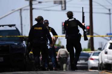 People carry weapons at the scene of a shooting outside the Islamic Center of San Diego Monday, May 18, 2026, in San Diego. (AP Photo/Gregory Bull)