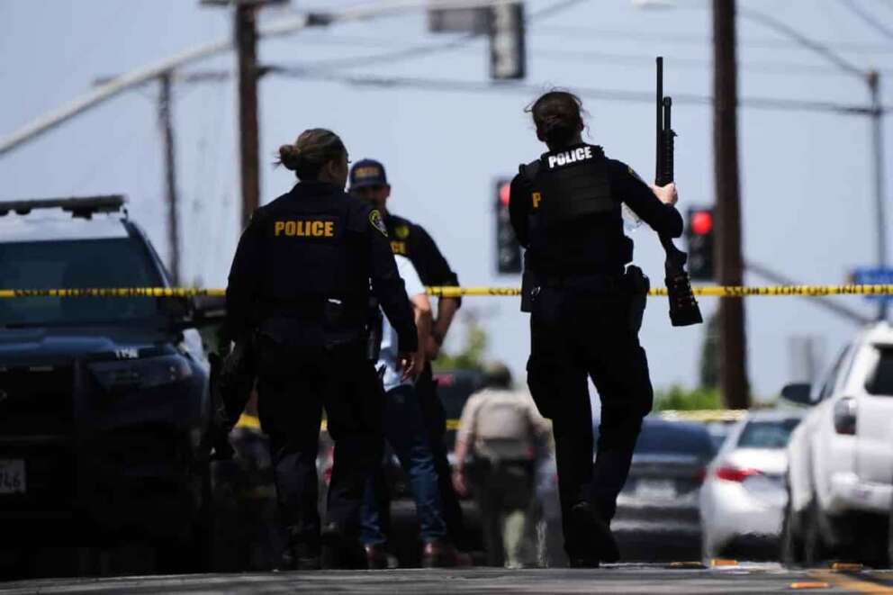People carry weapons at the scene of a shooting outside the Islamic Center of San Diego Monday, May 18, 2026, in San Diego. (AP Photo/Gregory Bull)