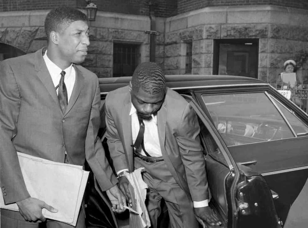 FILE – Co-defendants, from left, John Artis and Rubin “Hurricane” Carter, right, arrive at Pasaic County Courthouse Annex in Paterson, N.J., May 25, 1967. Artis, who was wrongly convicted with boxer Carter in a triple murder case that was publicized in a 1975 song by Bob Dylan and a 1999 film starring Denzel Washington, has died, Artis died at 75 on Nov. 7, 2021 of a gastric aneurysm at his home in Hampton, Va., said Fred Hogan, a longtime friend who who worked to help overturn the convictions of Artis and Carter. (AP Photo/Anthony Camerano, File)