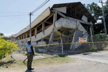 A policeman looks at an abandoned building that collapsed after an earthquake struck in Matanao, Davao del Sur province, Philippines on Monday June 8, 2026.(AP Photo/Nycel Basillote)