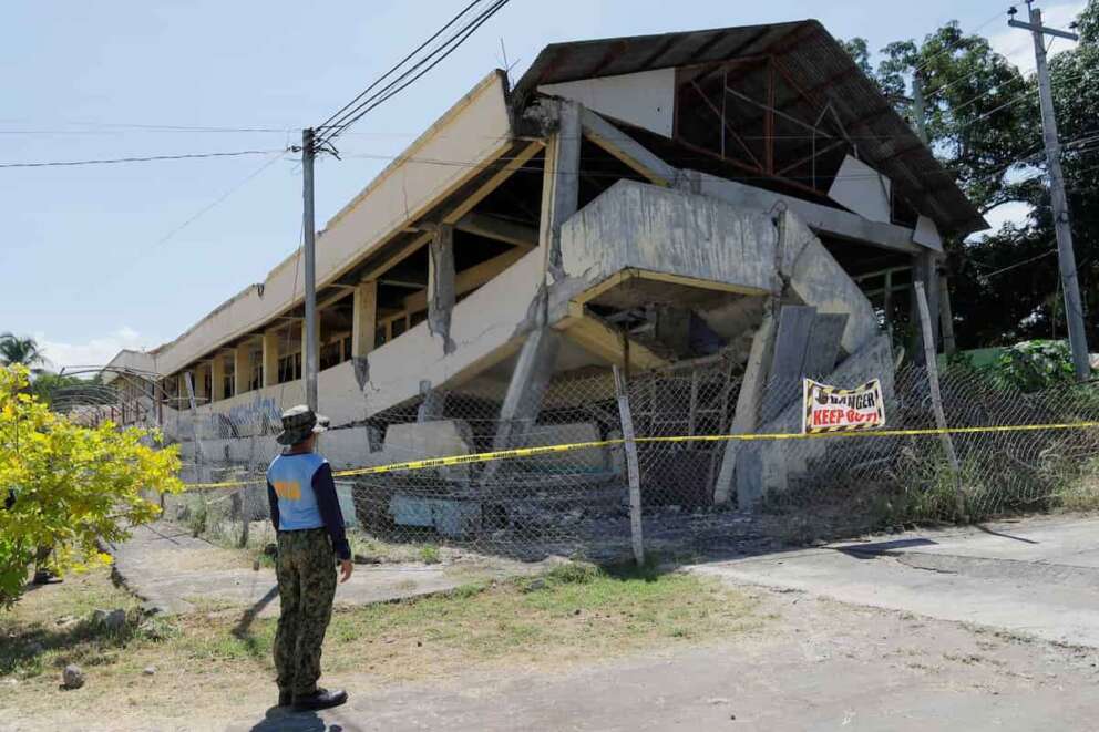 A policeman looks at an abandoned building that collapsed after an earthquake struck in Matanao, Davao del Sur province, Philippines on Monday June 8, 2026.(AP Photo/Nycel Basillote)