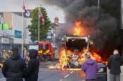 People watch as a vehicle burns during a protest in East Belfast following a stabbing incident in Belfast, Tuesday, June 9, 2026. (AP Photo/Peter Morrison)