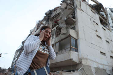 A woman walks past a building damaged during an earthquake in La Guaira, Venezuela, Thursday, June 25, 2026. (AP Photo/Pedro Mattey)
