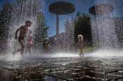 Children cool off in a public fountain in Vilnius, Lithuania, Saturday, June 27, 2026. (AP Photo/Mindaugas Kulbis)